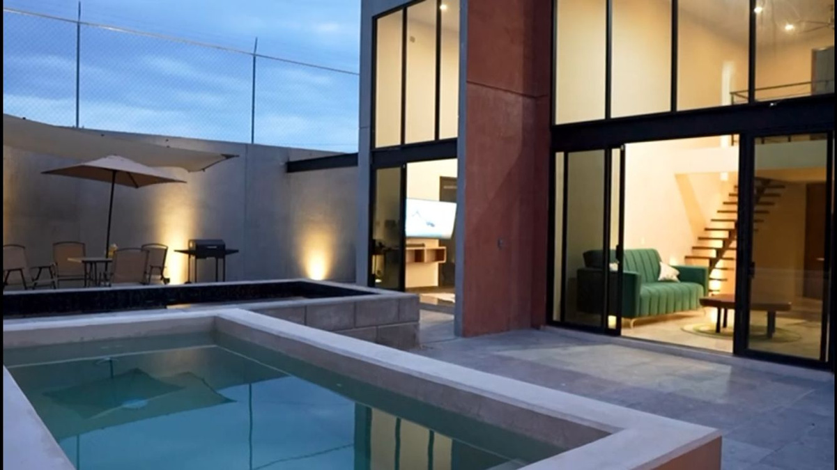 Casa contemporánea con alberca iluminada al atardecer