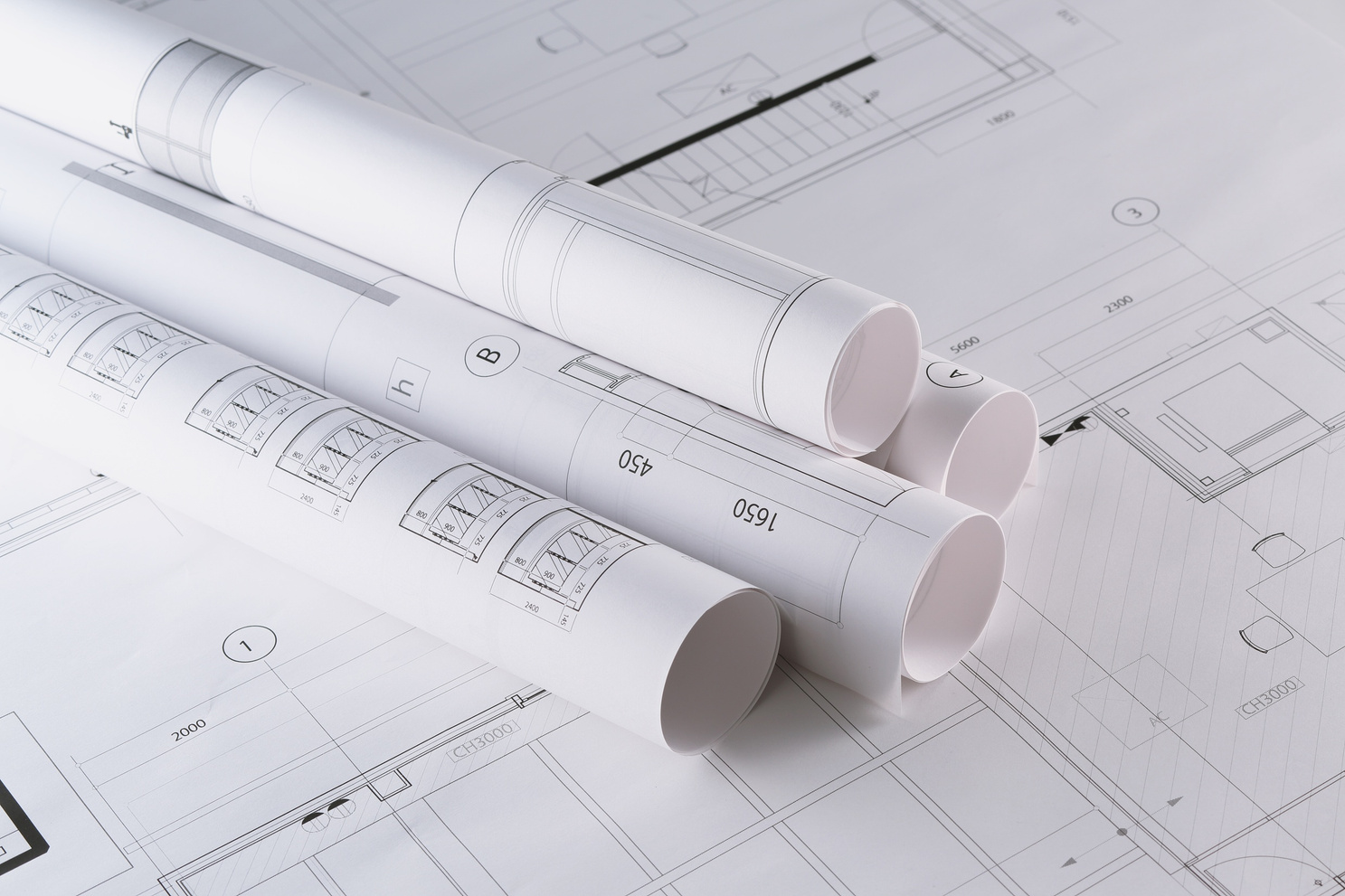 Planos arquitectónicos enrollados sobre una mesa de trabajo